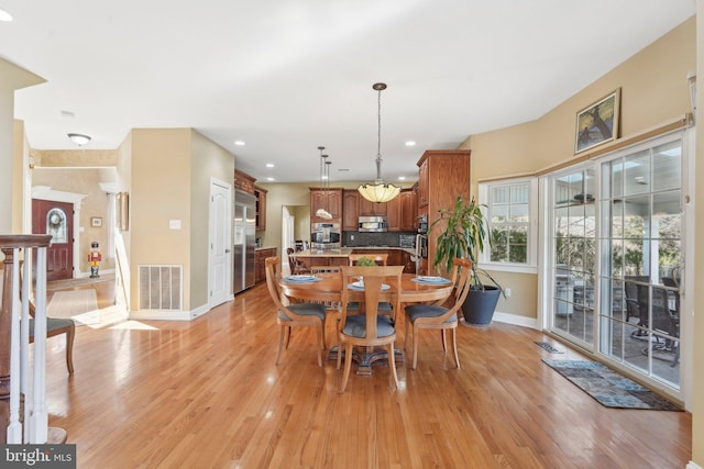 dining area with visible vents, light wood-type flooring, and baseboards