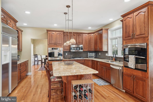 kitchen featuring backsplash, a center island, hanging light fixtures, stainless steel appliances, and a sink