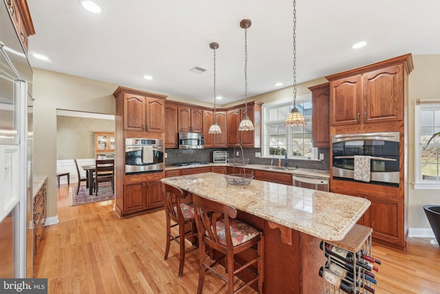 kitchen featuring backsplash, light wood-style floors, appliances with stainless steel finishes, and a center island