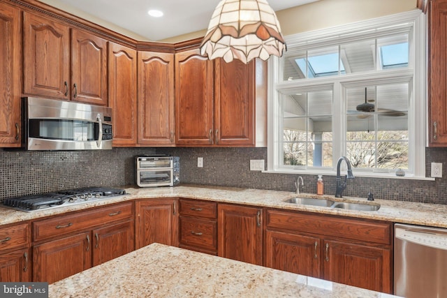 kitchen featuring light stone counters, a toaster, a sink, decorative backsplash, and stainless steel appliances