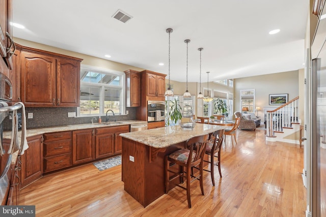 kitchen featuring visible vents, light wood-style flooring, stainless steel appliances, and a sink