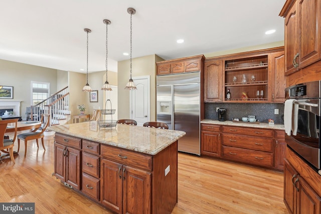 kitchen featuring open shelves, stainless steel appliances, a fireplace, and light wood finished floors