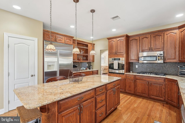 kitchen featuring visible vents, a kitchen island, light wood-style flooring, stainless steel appliances, and open shelves