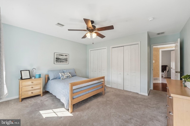 bedroom with baseboards, visible vents, multiple closets, and carpet floors