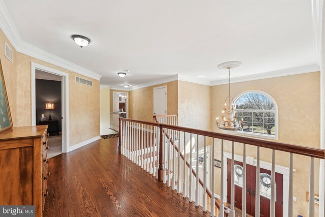 hallway with visible vents, an upstairs landing, wood finished floors, crown molding, and a chandelier