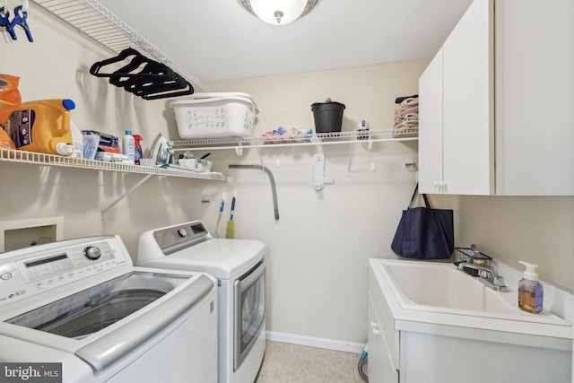 laundry room featuring washing machine and dryer, cabinet space, and baseboards