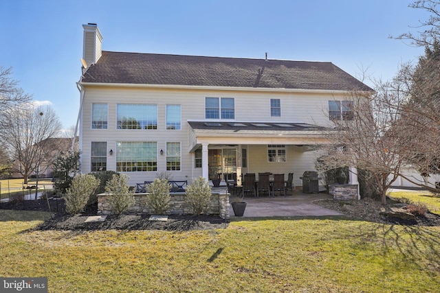 back of property featuring a yard, a chimney, and a patio area