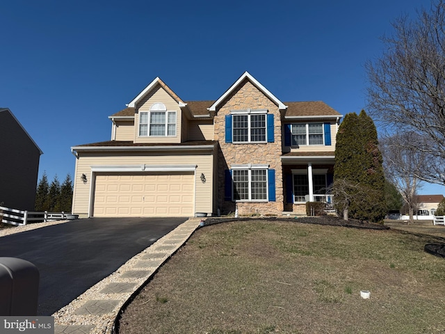 traditional-style home with stone siding, an attached garage, driveway, and a front lawn