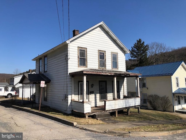 view of front facade with a porch and a chimney