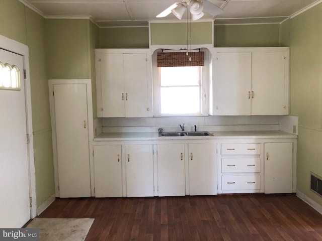 kitchen with a sink, ceiling fan, light countertops, white cabinets, and dark wood-style flooring