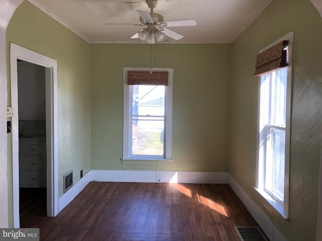 spare room with visible vents, baseboards, wood finished floors, and crown molding