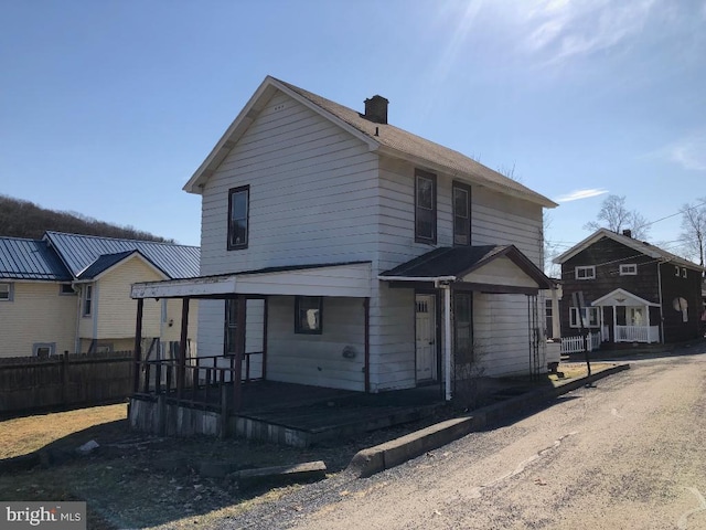 view of front of home with a chimney and fence