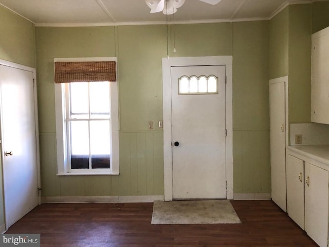 foyer featuring ornamental molding, a ceiling fan, dark wood-style flooring, and wainscoting