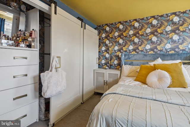 carpeted bedroom featuring wallpapered walls and a barn door