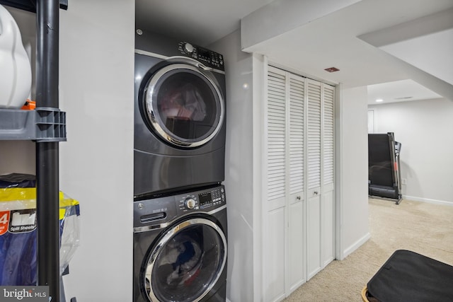 washroom with laundry area, stacked washer and dryer, baseboards, and carpet floors