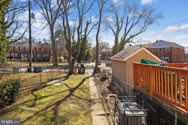 view of yard featuring a residential view, an outdoor structure, central AC, and fence