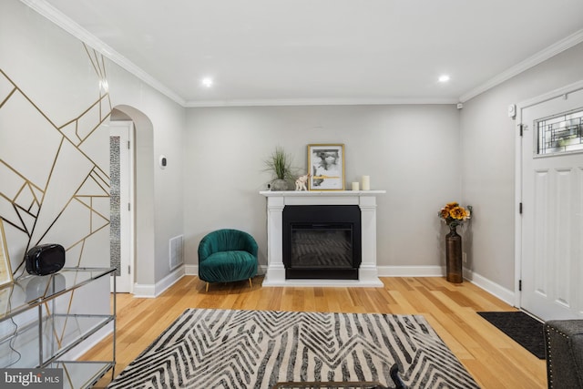 entryway with wood finished floors, visible vents, arched walkways, a glass covered fireplace, and crown molding