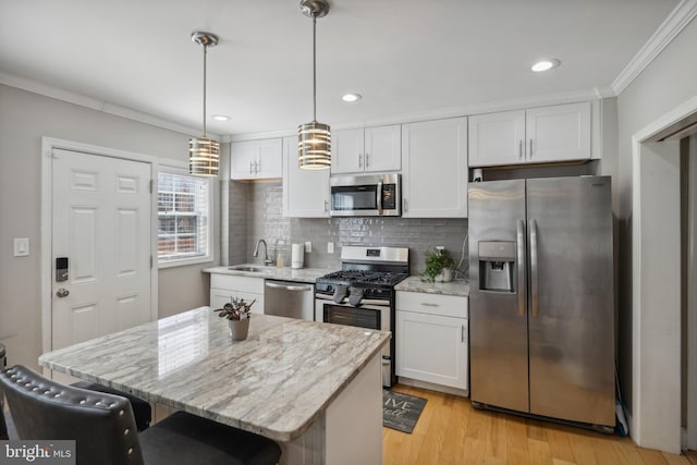 kitchen featuring white cabinets, appliances with stainless steel finishes, a kitchen island, and ornamental molding