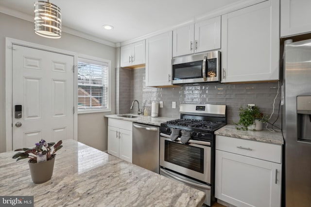 kitchen featuring stainless steel appliances, backsplash, crown molding, and white cabinetry