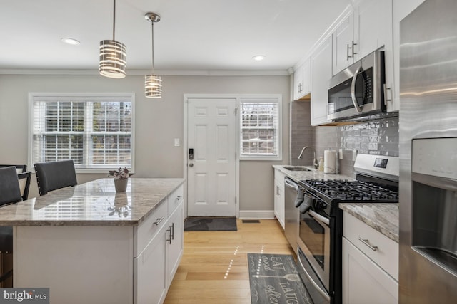 kitchen featuring decorative backsplash, light wood-style flooring, appliances with stainless steel finishes, and ornamental molding