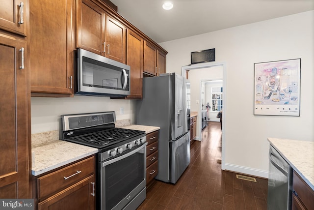 kitchen with visible vents, dark wood-type flooring, baseboards, light stone countertops, and appliances with stainless steel finishes