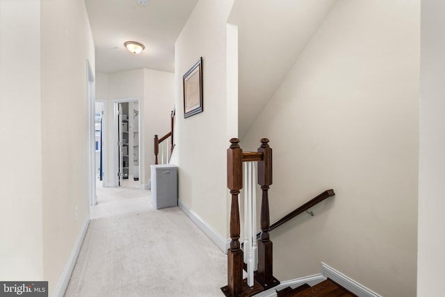 hallway with baseboards, carpet floors, and an upstairs landing