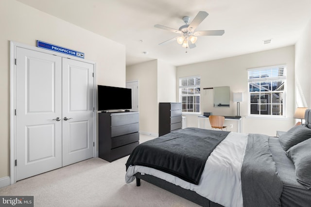 bedroom with visible vents, light colored carpet, a closet, and a ceiling fan