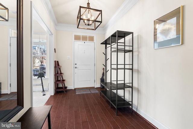 foyer entrance with baseboards, a notable chandelier, ornamental molding, and dark wood finished floors