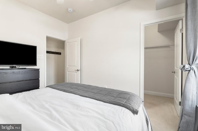 carpeted bedroom featuring a closet, a spacious closet, and baseboards