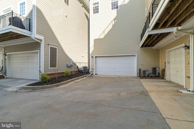 view of side of property featuring a balcony, central AC unit, and a garage