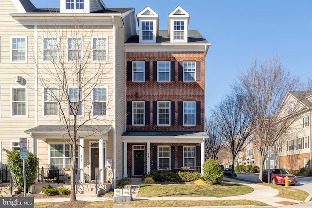 view of front of house featuring brick siding, covered porch, and a front lawn