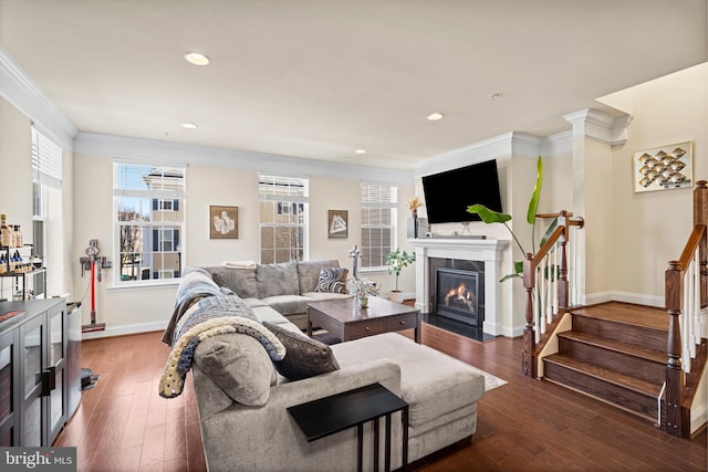 living room with stairway, baseboards, a fireplace with flush hearth, wood-type flooring, and crown molding