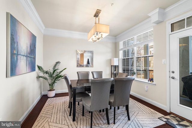 dining area featuring baseboards, wood finished floors, ornamental molding, and a chandelier