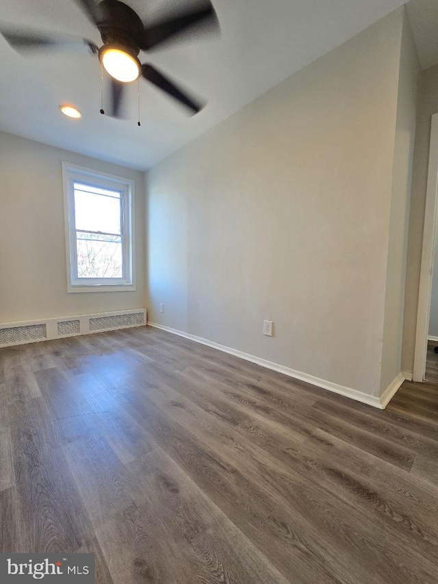 unfurnished room featuring dark wood-type flooring, a ceiling fan, and baseboards