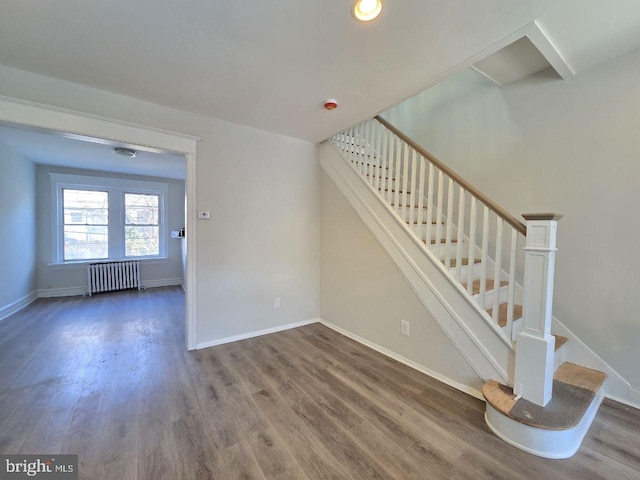 stairs featuring radiator, wood finished floors, and baseboards