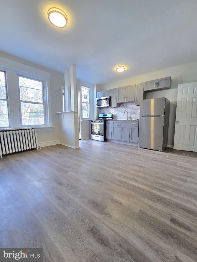 kitchen featuring gray cabinets, a sink, plenty of natural light, radiator, and appliances with stainless steel finishes