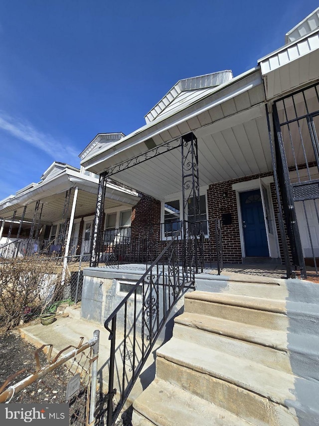 entrance to property featuring brick siding and a porch