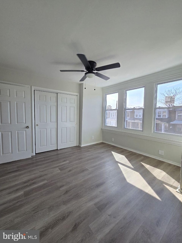 unfurnished bedroom featuring a closet, multiple windows, and dark wood finished floors