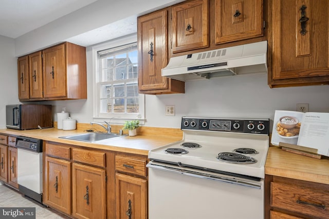 kitchen with brown cabinets, under cabinet range hood, a sink, white appliances, and light countertops