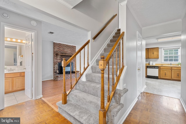 staircase with crown molding, a fireplace, baseboards, and a textured ceiling