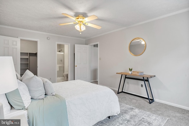 carpeted bedroom featuring a spacious closet, connected bathroom, baseboards, ornamental molding, and a textured ceiling