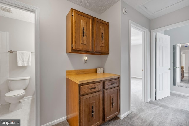 interior space featuring visible vents, baseboards, a textured ceiling, and toilet