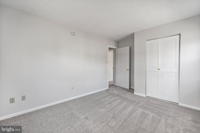 unfurnished bedroom featuring a closet, baseboards, a textured ceiling, and carpet floors