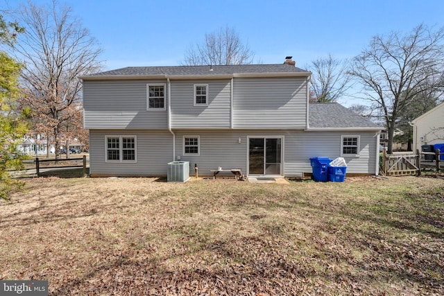 back of property with cooling unit, a lawn, fence, and a chimney