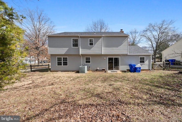 back of property with cooling unit, a chimney, a yard, and fence