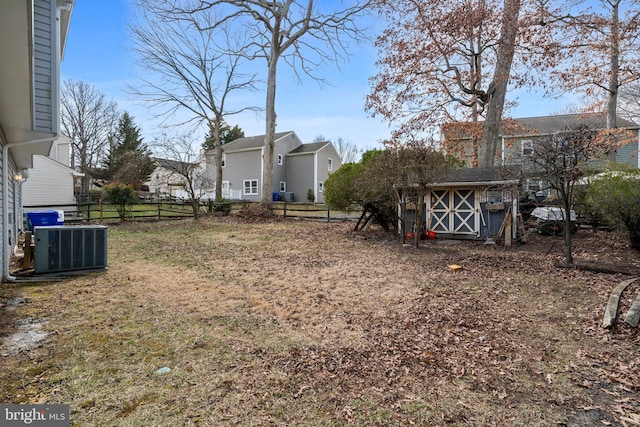 view of yard featuring an outbuilding, a storage unit, central AC, and fence