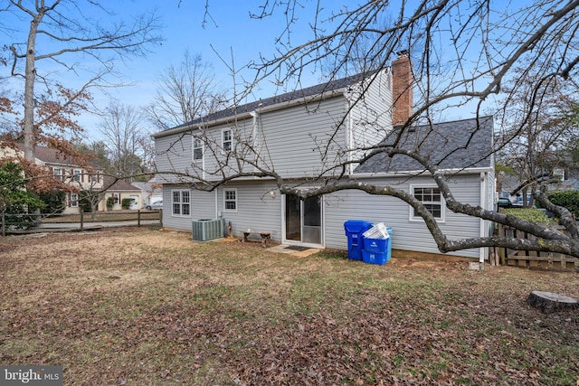 back of house with cooling unit, a chimney, a yard, and fence