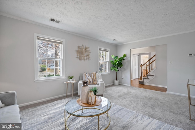 living area featuring visible vents, crown molding, baseboards, carpet, and stairway