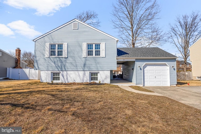 view of front of home with a front lawn, concrete driveway, an attached garage, and fence