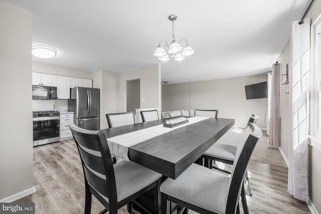 dining room featuring a notable chandelier, baseboards, and light wood-type flooring